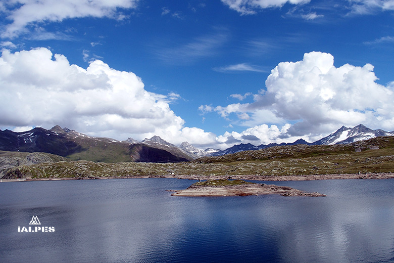 Lac Totensee au sommet du col du Grimsel avec montagnes enneigées en arrière-plan.